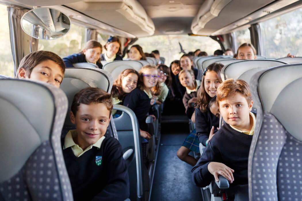 A group of smiling children sitting on a bus, enjoying a field trip.